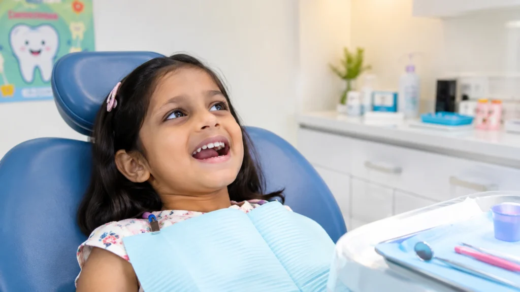 Pediatric dentist gently cleaning a smiling child's teeth with a small dental tool